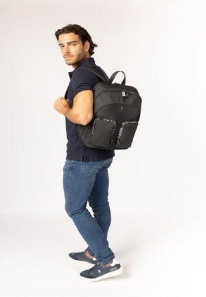 Zaino in tessuto nero con due tasche frontali, chiusura con cerniera e spallacci regolabili. Texture liscia con dettagli del logo e accenti a fantasia.