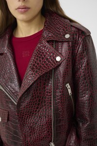 Red and black faux leather biker jacket with croc texture, silver zippers, snap buttons, and a wide collar. Underneath is a red top.