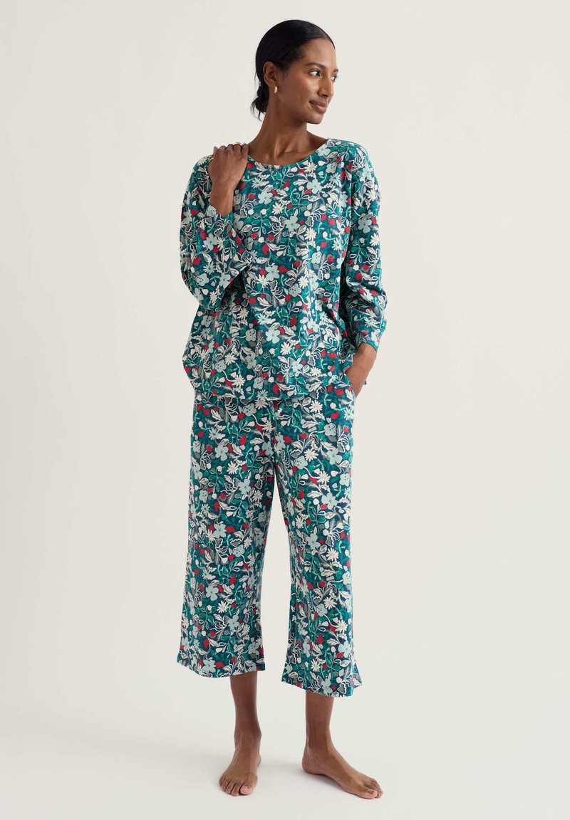 Zestaw odzieży wypoczynkowej z kwiatowym nadrukiem w kolorze morskim, składający się z luźnej bluzki z długim rękawem i krótkich spodni. Miękki materiał z kieszeniami i zaokrąglonym dołem.