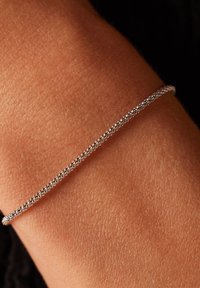 Silver beaded bracelet against a skin-toned wrist, featuring a smooth, thin design with a delicate texture and subtle shine.