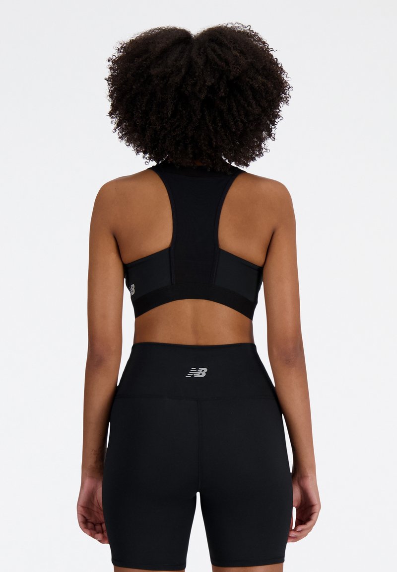 Soutien-gorge de sport noir avec un design dos nageur, en tissu texturé, et logo. Assorti à un short noir taille haute arborant un logo similaire.