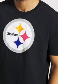 Czarny t-shirt z bawełny z okrągłym logo Pittsburgh Steelers w odcieniach żółtego, różowego, czerwonego i niebieskiego oraz napisem "Steelers."
