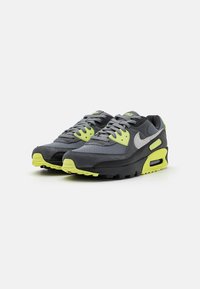 Pair of gray and black Nike Air Max sneakers with neon yellow accents and laces, shown at an angle on a white background.