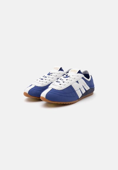Paire de baskets bleu et blanc à lacets, semelles marron, grand motif blanc « "M" » sur les côtés et logo Marc Jacobs sur la languette.