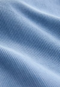 Light blue ribbed fabric with soft texture, featuring vertical stripes that create a gentle wave effect. No discernible patterns or accents.