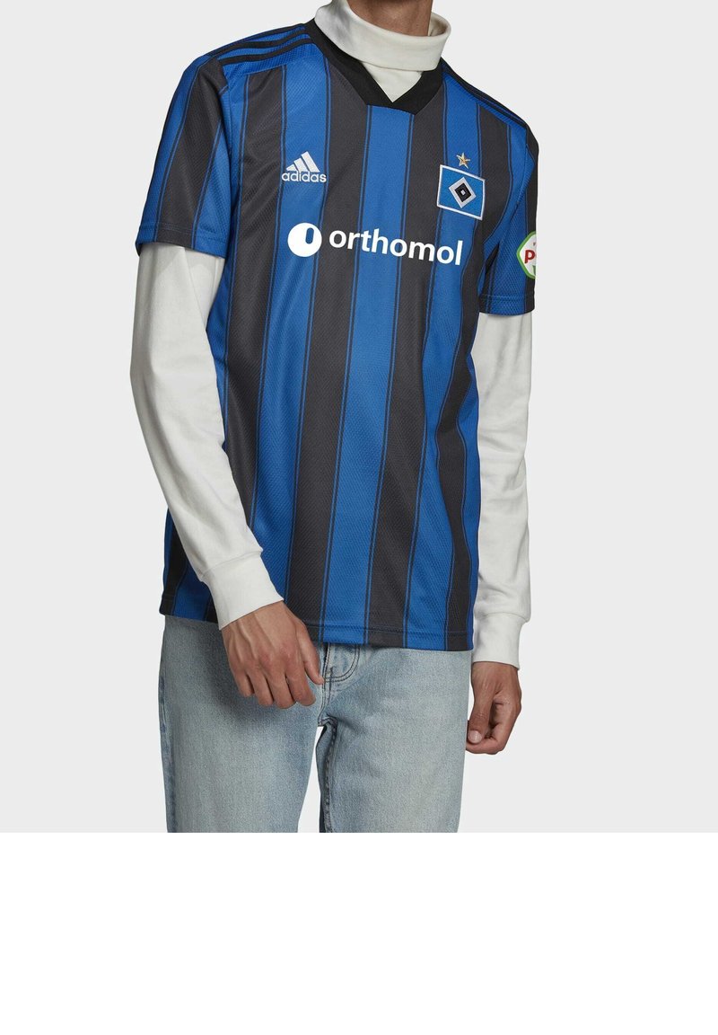 Modrý a černý pruhovaný fotbalový dres s výstřihem do V, krátkými rukávy a logem Adidas; kombinovaný s bílou košilí s dlouhými rukávy pod ním.