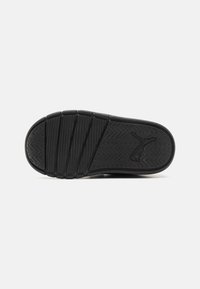Semelle de sneaker noire en caoutchouc présentant un motif en vagues, des stries et un logo en relief sur le côté. Texturée pour offrir une bonne adhérence et une durabilité.