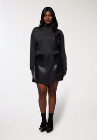 Długi rękaw, ciemnoszary top o luźnym kroju; w połączeniu z czarną, sztuczną skórzaną mini spódnicą z rozcięciem z przodu. Czarne skarpetki i wyciągane baleriny.
