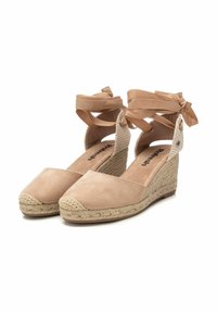 Cuñas de esparto en ante beige con tacón de yute trenzado. Presentan cintas alrededor del tobillo, lados abiertos y plantilla acolchada para mayor comodidad.