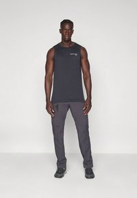 Čierne atletické tielko bez rukávov s logom, v kombinácii s tmavosivými cargo nohavicami s vreckami a textúrovaným vzorom.