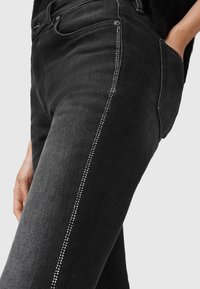 Zwarte denim jeans met een slanke pasvorm, gedetailleerde strasssteentjes langs het zijnaden, en een klassiek ontwerp met vijf zakken.