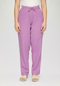 Pantalons en lin violet clair avec une coupe décontractée, taille à cordon réglable et texture subtile. Associés à des sandales à lanières de couleur claire.