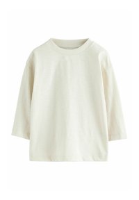 Lys beige langærmet t-shirt lavet af blød bomuld. Har en rund halsudskæring og en afslappet, let oversized pasform. Glat tekstur, ingen udsmykninger.