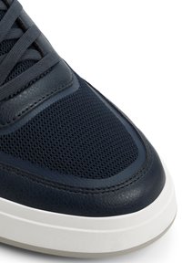 Sneaker blu scuro con tomaia in pelle e mesh, dotato di punta arrotondata, motivo testurizzato e dettagli bianchi sulla suola.