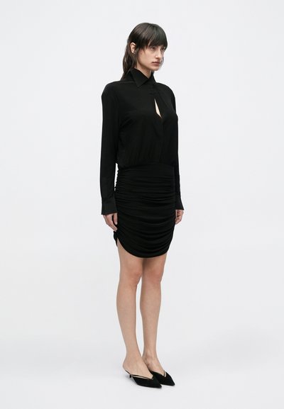 Juoda suknelė ilgomis rankovėmis, su apykakle ir raktelio formos iškirpte. Surinkta tekstūra ties juosmeniu, aptemptas siluetas ir šoninis plyšys.