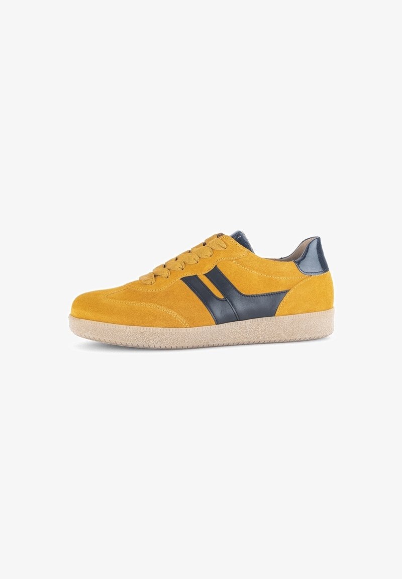 Baskets en suède jaune avec des bandes latérales en cuir noir, semelle en caoutchouc beige et lacets, vues de côté sur fond blanc.