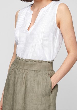 Mouwloze witte blouse met plooien en V-hals, gecombineerd met een olijfgroene hoge taille rok met elastische tailleband en zijzak.