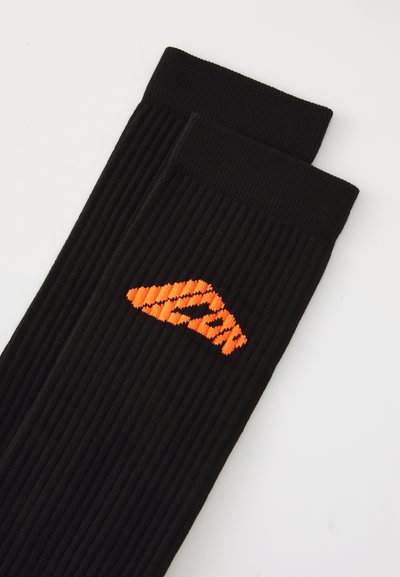 Pair of black ribbed socks with bright orange geometric logo embroidered near the cuff on a white background.