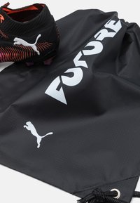 Čierny batoh na šnúrku s textúrovaným povrchom, s bielym logom "PUMA FUTURE" a emblemom skáčúcej mačky. Čiastočne je viditeľná futbalová kopačka.
