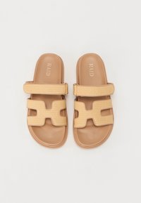 Gaišbrūnas slip-on sandales ar divām platām pārklājošām siksnām, kas izstrādātas ar austu tekstūru. Gluda, gaiši brūna zole ar diskrētu logo iepresējumu.