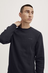 Sudadera azul marino oscura con cuello redondo, mangas largas y un sutil logo "blend" en el pecho. Tejido suave con una silueta ajustada.