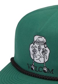 Green cap with black braided band features a white embroidered face with tears shaped like spoons and the word "VOLCOM" below it.
