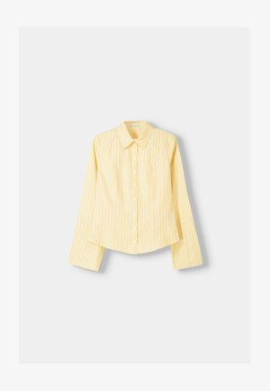 Camicia a righe gialle con maniche lunghe, colletto a punta e chiusura frontale con bottoni. Presenta righe verticali blu e una vestibilità sartoriale.