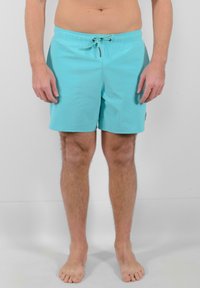 Pantaloni da bagno turchesi con vita elastica e cordoncino. Realizzati in un materiale leggero, con una texture liscia e cuciture ordinate.