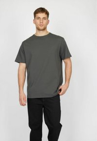 Mørkegrå bomulds-T-shirt med rund halsudskæring og korte ærmer, kombineret med sorte bukser. Simpel, lige snit og glat tekstur.
