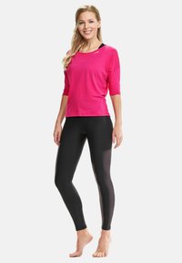Fuchsia top met driekwartmouwen, gecombineerd met zwarte leggings, beide gemaakt van rekbare stof met een zachte textuur en een eenvoudig ontwerp.