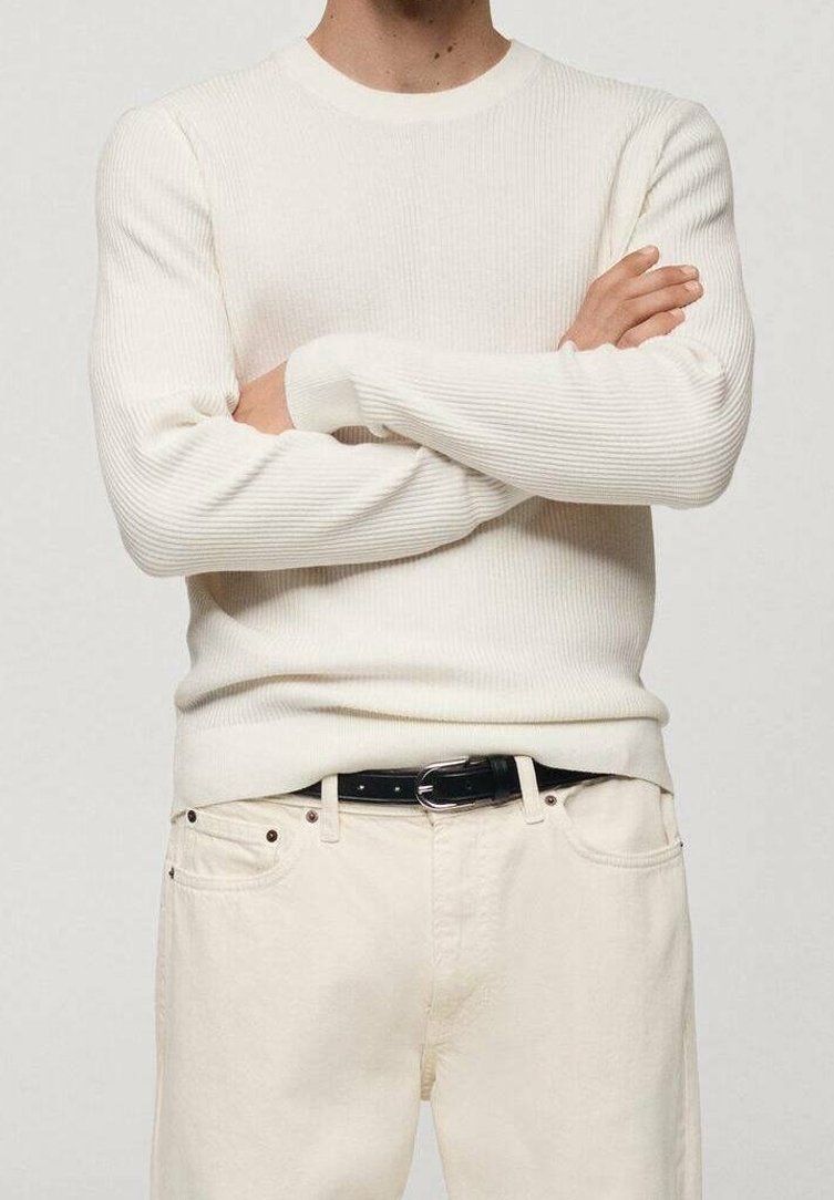 White ribbed long-sleeve sweater with a round neckline, paired with light-colored pants and a black belt. Neutral tones and textured fabric.