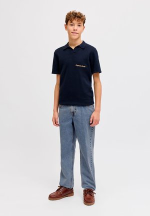 Navy polo shirt with short sleeves and embroidery, paired with light blue straight-leg jeans and brown lace-up shoes with rubber soles.