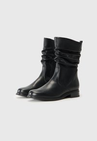 Svarta läder ankelskor med en slouchad design, slät yta och en diskret klack. Har sydda detaljer och en rund tå.