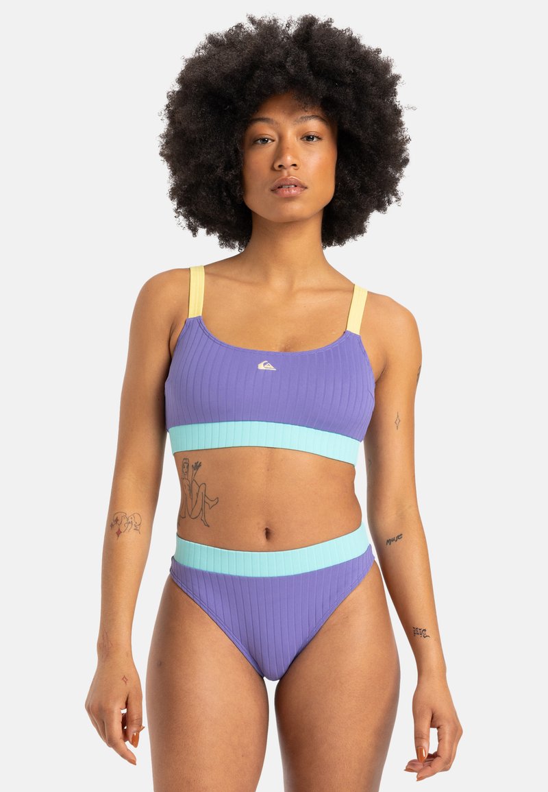 Lilla stripete bikini-sett med et crop-top med gule stropper og en aqua blå midjebånd på bunnene. Glatt tekstur, minimale design detaljer.