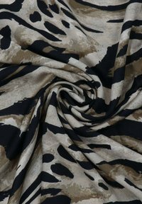 Tessuto stampato che presenta un mix di stampa animale beige e nera con strisce e macchie astratte, caratterizzato da una texture morbida e liscia.