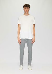 Witte katoenen t-shirt met korte mouwen, gecombineerd met lichtgrijze katoenen broek, afgemaakt met witte sneakers. Eenvoudig, minimalistisch ontwerp.