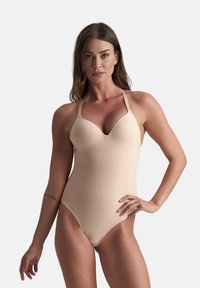 Beige baddräkt i ett stycke med justerbara band, formade kupor och ett mjukt, stretchigt material. Har en låg rygg och benöppningar.
