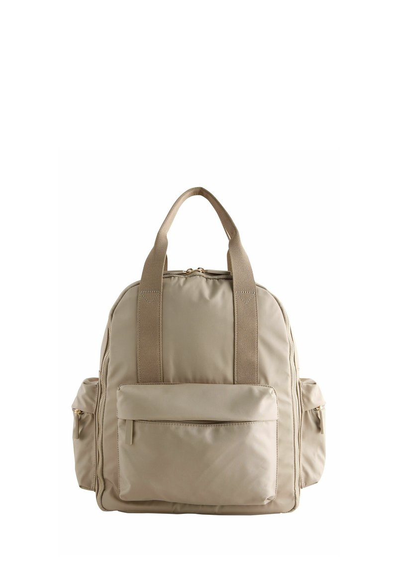Zaino in tessuto morbido beige con due manici anteriori, ampia tasca frontale con zip e tasche laterali con zip su sfondo bianco neutro.