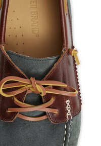 Zapato de cuero marrón y ante gris con cordones amarillos y marrones, costuras detalladas y un forro interior suave. Presenta una textura pronunciada y acentos.
