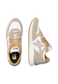 Sneaker beige e bianche realizzate in materiali scamosciati e in rete, con accenti beige testurizzati, suole in gomma marrone e logo laterale ben visibile.