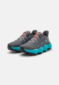 Scarpe da ginnastica grigie con suole turchesi, dotate di tomaia in rete, fori circolari e dettagli rossi sui lacci e sulla linguetta.