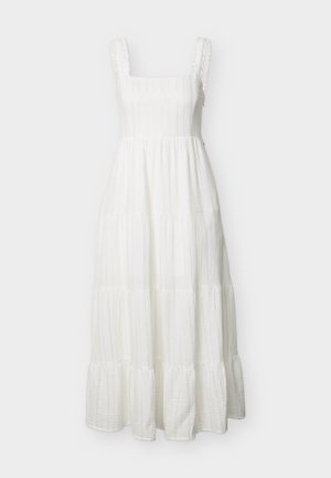 Robe maxi blanche sans manches avec encolure carrée, jupe à volants et fines rayures verticales texturées.