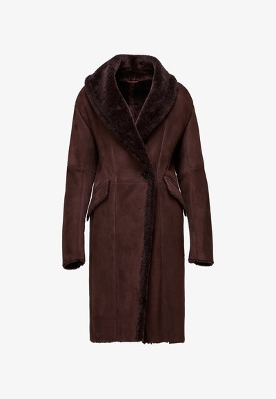 Lang mørkebrun ruskindfrakke med stor krave i lammeskind, knaplukning, sidelommer med klap og lammeskindskant på ærmekanter og forkanter.