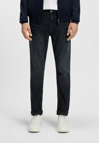 Ciemnoniebieskie dżinsy z prostymi nogawkami, z zapięciem na guzik, subtelnym przetarciem oraz pięcioma kieszeniami, w komplecie z białymi trampkami.