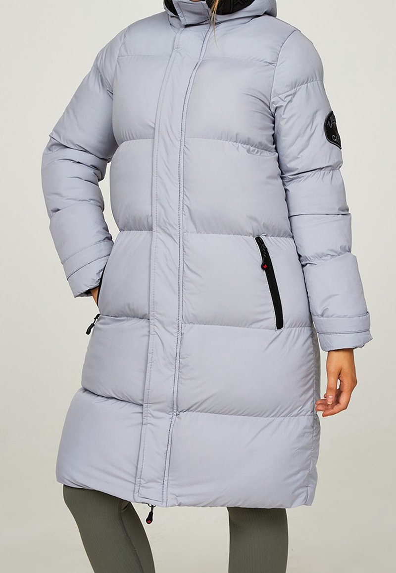 Hellgrauer, gesteppter Mantel mit Kapuze, vertikalen Nähten, seitlichen Reißverschlüssen und einem Logopatch am linken Ärmel. Glatte Textur und knielanges Design.