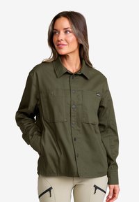 Olivgrön skjorta med knappar, två bröstfickor, långa ärmar och en strukturerad krage. Tillverkad av slitstarkt tyg med en slät yta.