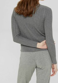 Grå ribbad tröja med en figurnära siluett, långa ärmar och en mjuk textur, i kombination med matchande grå byxor i en avslappnad passform.