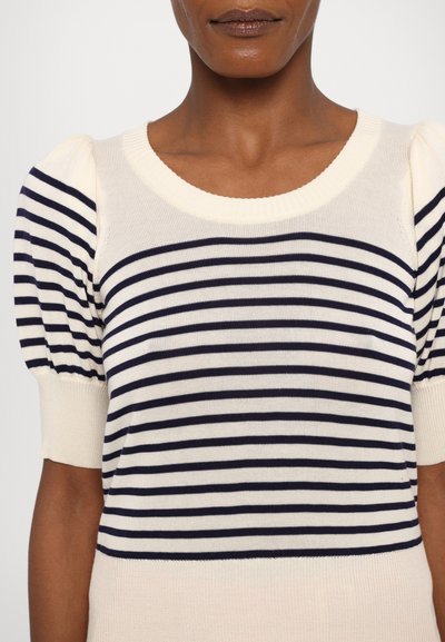 Stripete strikket topp med korte puffermer. Har marineblå og kremfargede striper, ribbet halslinning og myk tekstur.