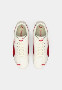 Scarpe sportive bianche con accenti rossi, design con lacci, tomaia morbida al tatto, soletta Ortholite e logo Puma sul lato e sulla linguetta.