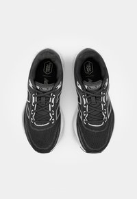 Baskets de sport noires avec une tige en maille, accents blancs, design texturé et semelle rembourrée. Comprend des lacets et un logo sur la languette.